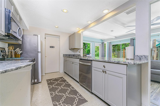 kitchen featuring a sink, gray cabinets, beamed ceiling, and stainless steel appliances