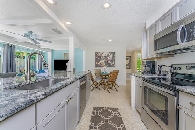 kitchen featuring stainless steel appliances, recessed lighting, a sink, and light stone counters