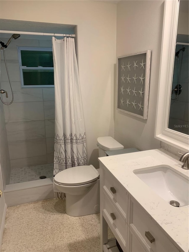 bathroom with toilet, vanity, speckled floor, and a stall shower