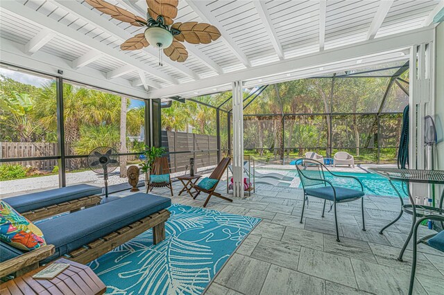 sunroom / solarium featuring beamed ceiling, ceiling fan, and a healthy amount of sunlight