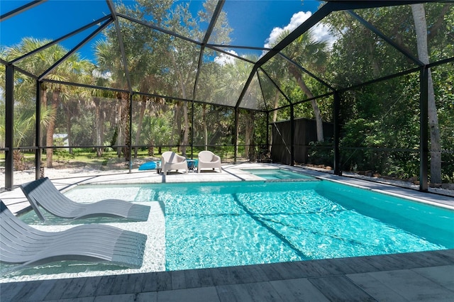 view of swimming pool with a patio, a pool with connected hot tub, and glass enclosure