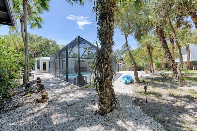 outdoor pool with a patio area, fence, and glass enclosure