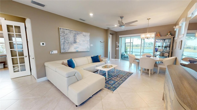living area featuring visible vents, ceiling fan with notable chandelier, and light tile patterned flooring