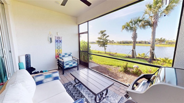 sunroom / solarium featuring ceiling fan and a water view