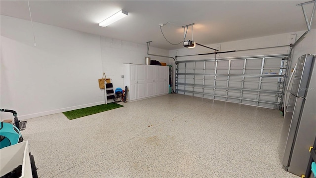 garage featuring baseboards, freestanding refrigerator, and a garage door opener