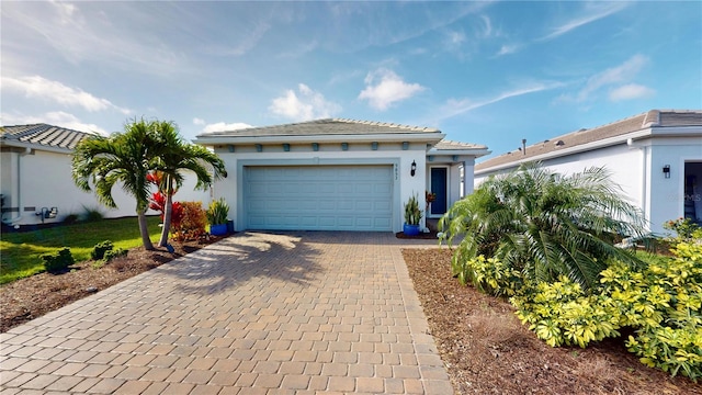 view of front of property with a tiled roof, a garage, stucco siding, and decorative driveway