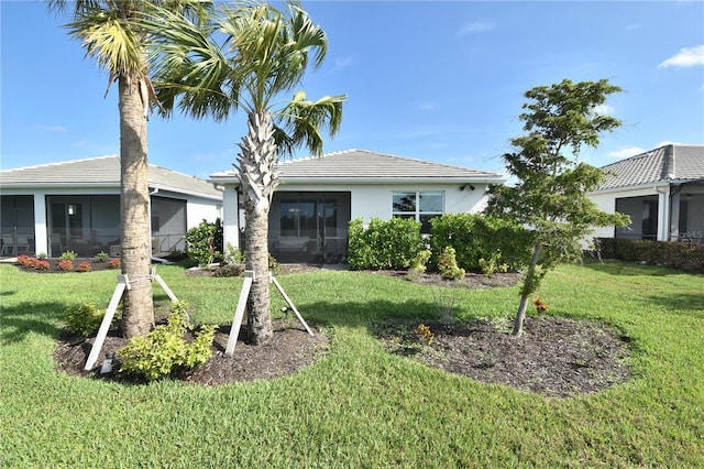 back of property featuring a yard, stucco siding, and a sunroom