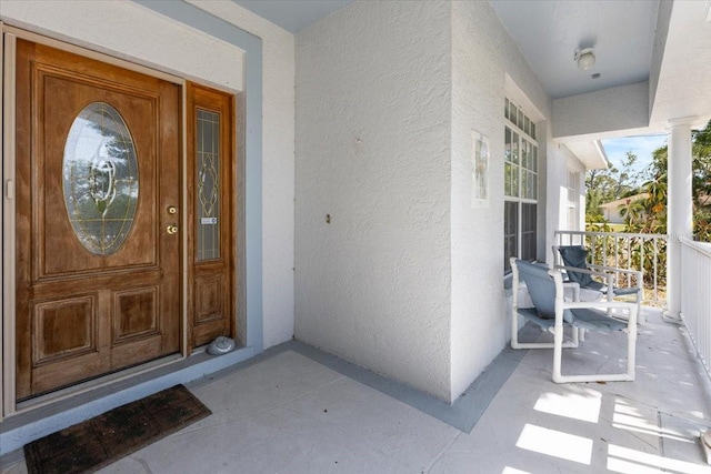 property entrance with covered porch and stucco siding