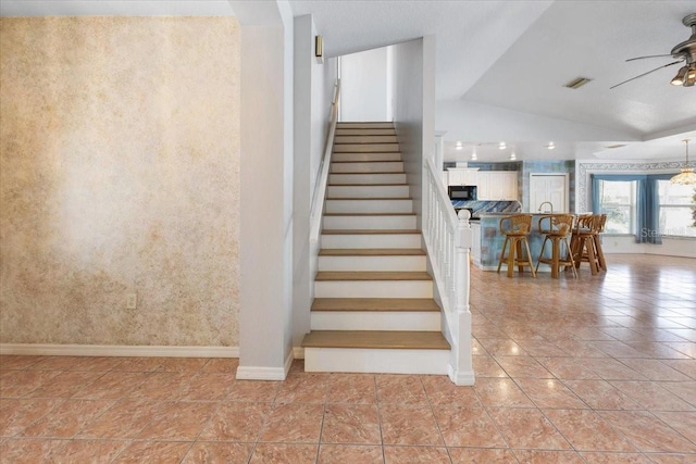 stairway with tile patterned floors, vaulted ceiling, visible vents, wallpapered walls, and ceiling fan