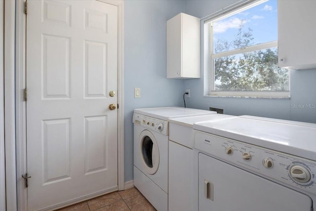 clothes washing area with baseboards, cabinet space, washer and clothes dryer, and light tile patterned floors