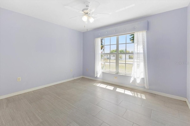 spare room with baseboards and a ceiling fan