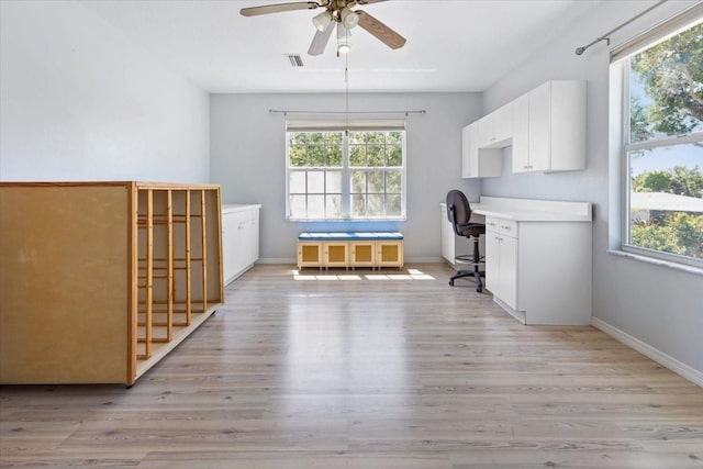 unfurnished office featuring light wood-type flooring, a wealth of natural light, and a ceiling fan