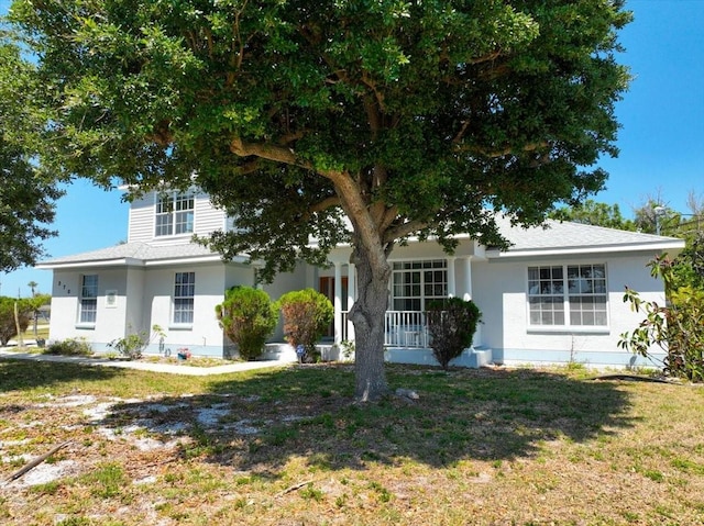 view of front of house featuring stucco siding, a front lawn, and a porch