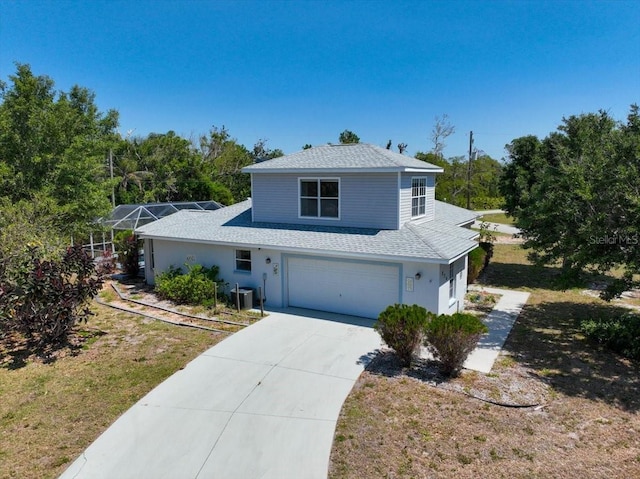 traditional home featuring central AC unit, driveway, an attached garage, a front yard, and roof with shingles