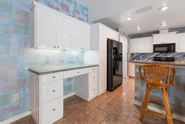 kitchen featuring tasteful backsplash, visible vents, white cabinetry, built in study area, and black appliances