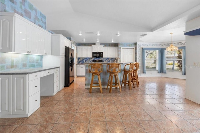 kitchen with tasteful backsplash, vaulted ceiling, white cabinetry, a breakfast bar, and black appliances
