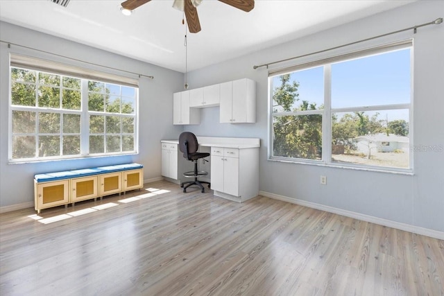 home office with light wood-type flooring, plenty of natural light, a ceiling fan, and baseboards