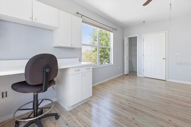 office space featuring built in desk, light wood finished floors, baseboards, and ceiling fan