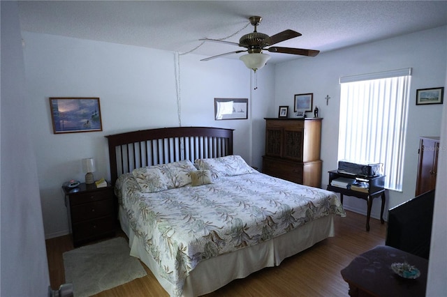 bedroom featuring baseboards, wood finished floors, and ceiling fan