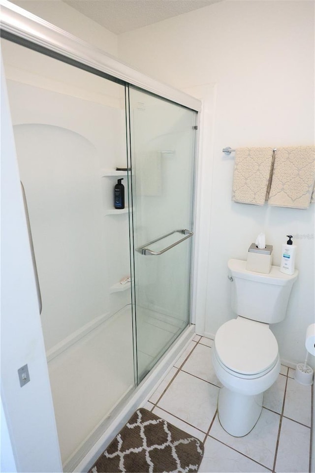 full bath with tile patterned floors, toilet, and a stall shower