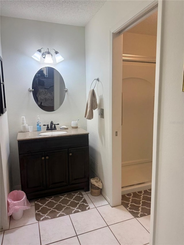 full bathroom with a shower, a textured ceiling, vanity, and tile patterned flooring