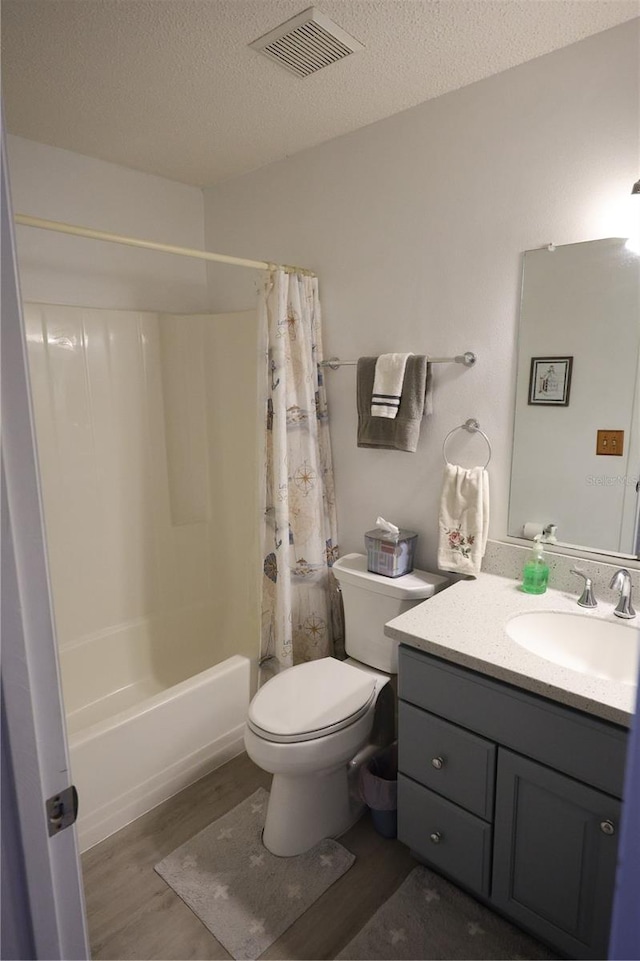 bathroom featuring vanity, toilet, visible vents, a textured ceiling, and wood finished floors