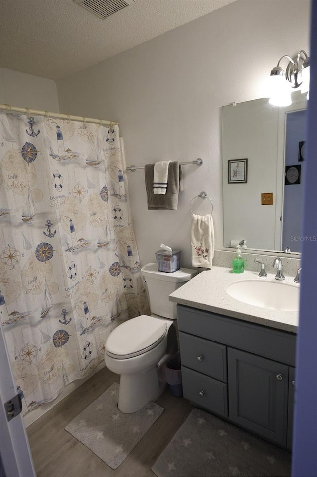 bathroom with visible vents, wood finished floors, toilet, and vanity