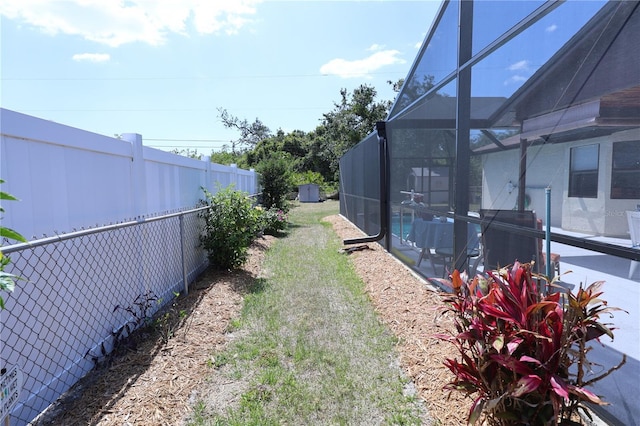 view of yard featuring glass enclosure and a fenced backyard