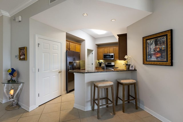 8500 Amberjack Cir Unit 102, Englewood, FL 34224 - kitchen with dark stone countertops, light tile patterned floors, a peninsula, tasteful backsplash, and appliances with stainless steel finishes