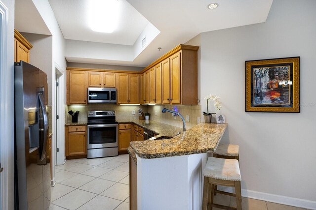 8500 Amberjack Cir Unit 102, Englewood, FL 34224 - kitchen featuring tasteful backsplash, a sink, a breakfast bar, a peninsula, and appliances with stainless steel finishes