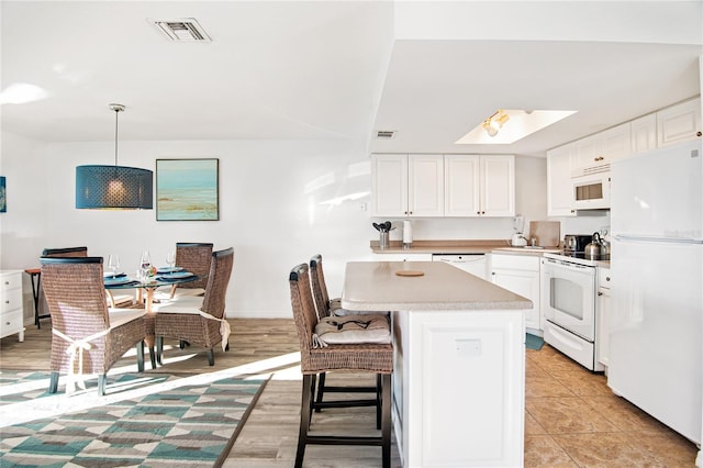 kitchen featuring a sink, white appliances, light countertops, white cabinetry, and visible vents