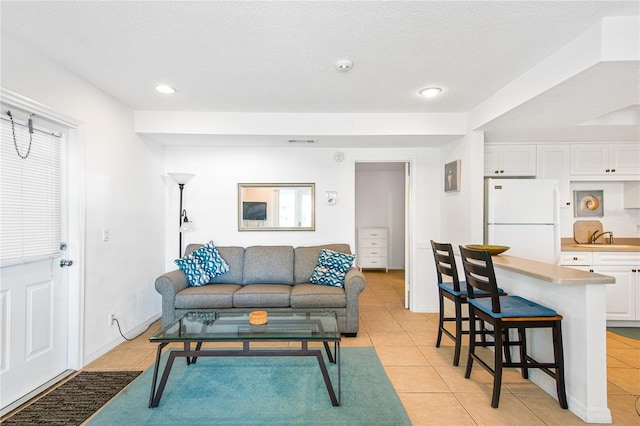 living room featuring a textured ceiling, recessed lighting, light tile patterned flooring, and visible vents