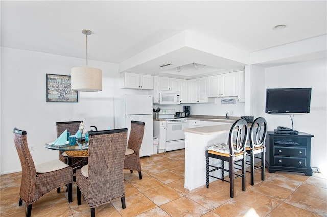 kitchen with visible vents, a peninsula, white appliances, white cabinetry, and decorative light fixtures