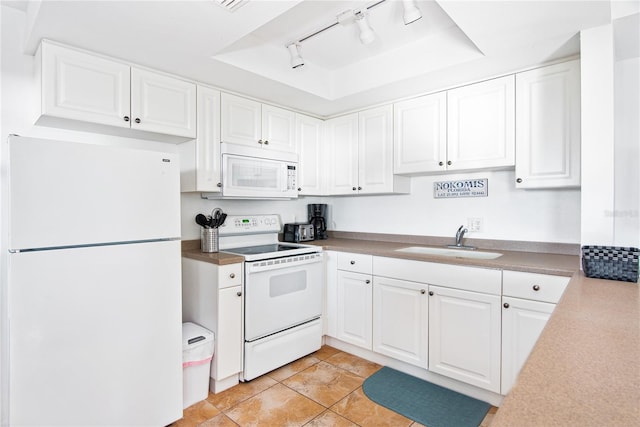 kitchen with track lighting, a sink, white appliances, white cabinetry, and a tray ceiling