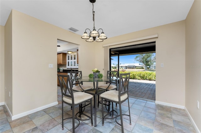 39 Bunker Pl, Rotonda West, FL 33947 - dining area featuring stone tile flooring, baseboards, visible vents, and a notable chandelier