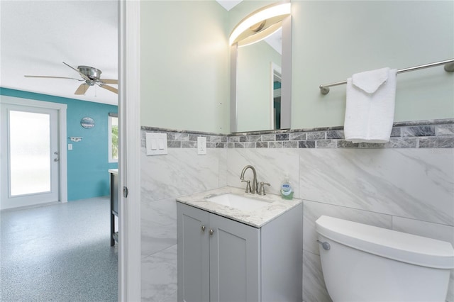 1245 Gulf Blvd, Englewood, FL 34223 - half bath with vanity, toilet, tile walls, a wainscoted wall, and a ceiling fan