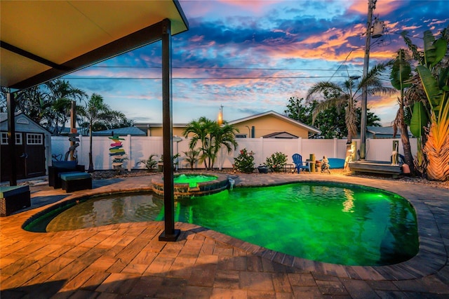 1245 Gulf Blvd, Englewood, FL 34223 - pool at dusk featuring a fenced backyard, an outbuilding, a pool with connected hot tub, and a shed