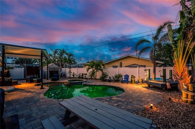 1245 Gulf Blvd, Englewood, FL 34223 - pool at dusk with an in ground hot tub, a storage shed, a patio area, a fenced in pool, and a fenced backyard