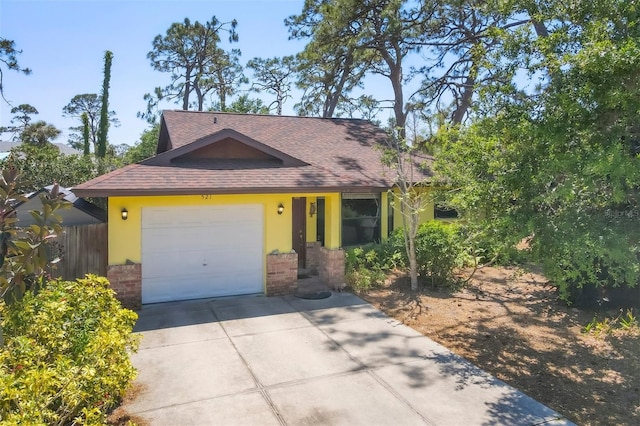 view of front of home with an attached garage, driveway, fence, and roof with shingles
