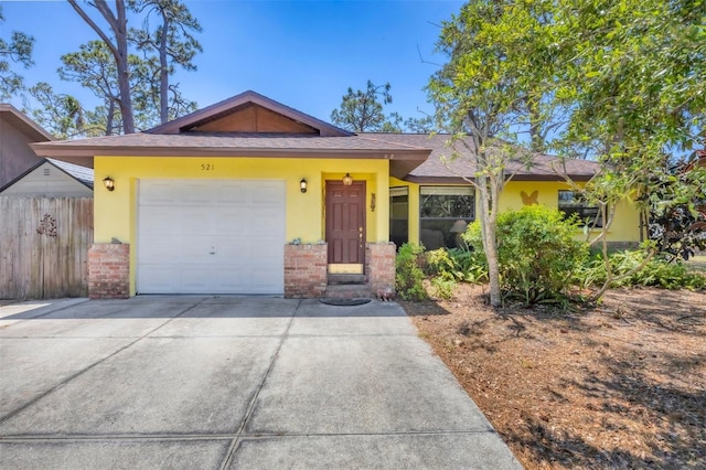 ranch-style home featuring brick siding, concrete driveway, and stucco siding