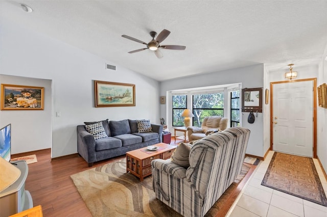 living area featuring vaulted ceiling, a ceiling fan, light wood-type flooring, baseboards, and visible vents