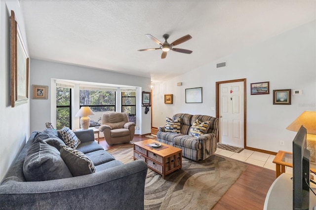 living area with vaulted ceiling, visible vents, light wood-type flooring, and ceiling fan