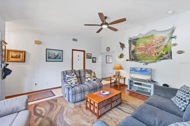 living area with visible vents, a ceiling fan, and baseboards