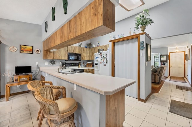 kitchen featuring a peninsula, black microwave, light countertops, white fridge with ice dispenser, and light tile patterned floors