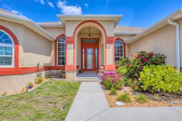 property entrance with stucco siding and roof with shingles