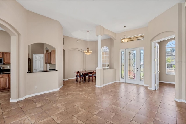 foyer with arched walkways and baseboards