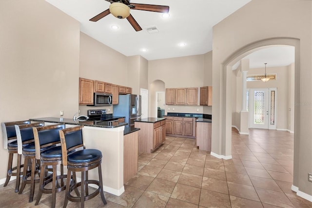 kitchen featuring ceiling fan, visible vents, baseboards, arched walkways, and appliances with stainless steel finishes
