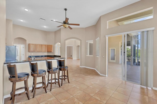 kitchen featuring dark countertops, arched walkways, a ceiling fan, and freestanding refrigerator