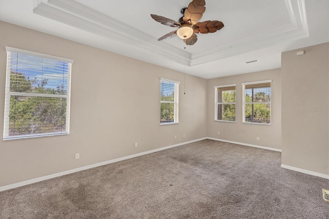 spare room featuring crown molding, a raised ceiling, baseboards, carpet, and a ceiling fan
