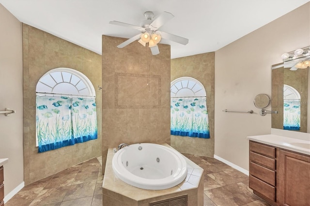 full bath with a whirlpool tub, a ceiling fan, vanity, and a healthy amount of sunlight